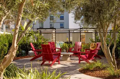a group of red chairs sitting on a patio at Homewood Suites By Hilton Long Beach Airport in Long Beach