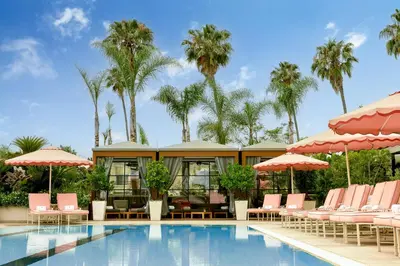 a pool with chairs and umbrellas and palm trees at Four Seasons Hotel Los Angeles at Beverly Hills in Los Angeles