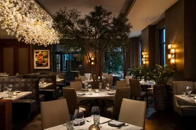 a restaurant with tables and chairs and a chandelier at Four Seasons Hotel Los Angeles at Beverly Hills in Los Angeles
