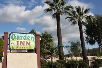 a sign for a garden inn and suites with palm trees at Garden Inn and Suites Glendora in Glendora