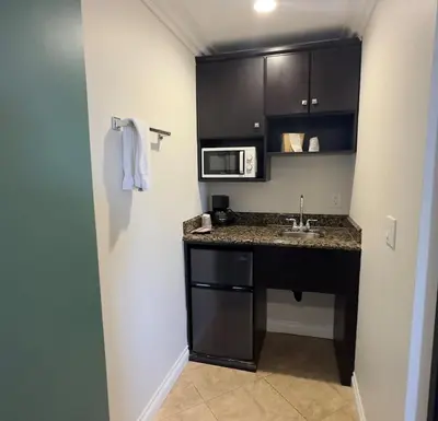 a small kitchen with a sink and a microwave at Garden Inn and Suites Glendora in Glendora