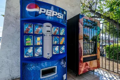 a pepsi machine sitting next to a gate at Motel 6-Redlands, CA in Redlands