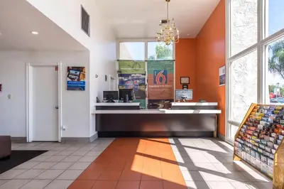 a store lobby with orange walls and a large window at Motel 6-Redlands, CA in Redlands