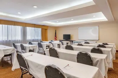 a conference room with tables and chairs and a screen at Best Western Plus West Covina Inn in West Covina