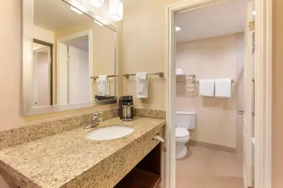 a bathroom with a sink and a toilet and a mirror at Best Western Plus West Covina Inn in West Covina