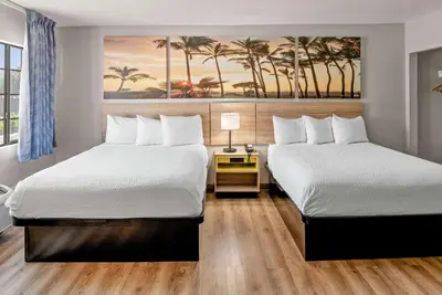 two beds in a hotel room with palm trees at Days Inn & Suites by Wyndham Artesia in Artesia