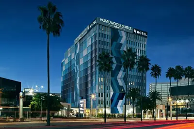 a tall glass building with palm trees in front of it at H Hotel Los Angeles, Curio Collection By Hilton in Los Angeles