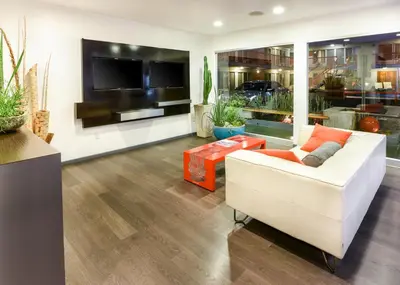 a living room with a white couch and a tv at The Tangerine - a Burbank Hotel in Burbank