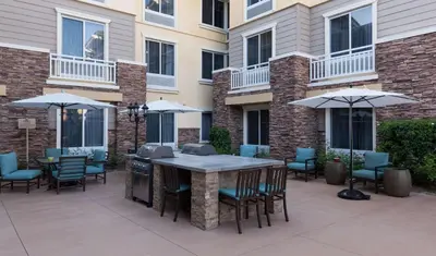 a patio with a table and chairs and umbrellas at Homewood Suites by Hilton Agoura Hills in Agoura Hills