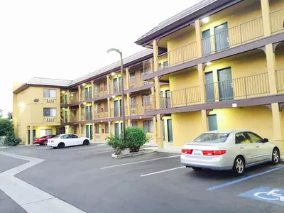 two cars parked in a parking lot in front of a building at Simply Home Inn & Suites - Riverside in Riverside
