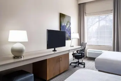 a hotel room with a desk with a television and a bed at Hilton Garden Inn Bakersfield in Bakersfield