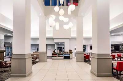 a lobby with white columns and red chairs at Hilton Garden Inn Bakersfield in Bakersfield