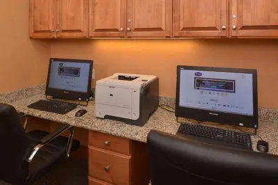 two computers on a desk with a printer and a laptop at Hampton Inn and Suites Bakersfield North-Airport in Bakersfield