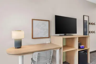 a room with a desk with a television and a lamp at Spark by Hilton Bakersfield Central in Bakersfield