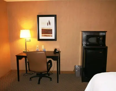 a hotel room with a desk with a microwave and a bed at Hampton Inn and Suites Barstow in Barstow