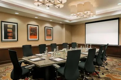 a conference room with a table and chairs and a projection screen at Embassy Suites Los Angeles Glendale in Glendale