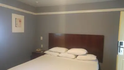 a bedroom with a bed with three pillows on it at Riviera Motel in Anaheim