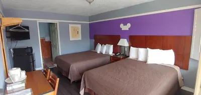 a hotel room with two beds and purple walls at Riviera Motel in Anaheim