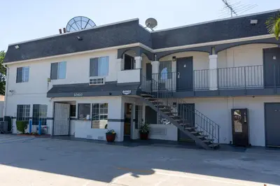 a large white building with a staircase on it at Value Inn Bellflower in Bellflower