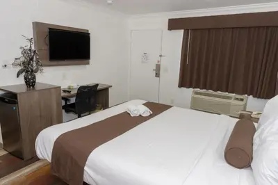 a hotel room with a bed and a desk and a television at Value Inn Bellflower in Bellflower