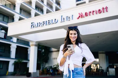 a woman standing in front of a building looking at her cell phone at Fairfield by Marriott Anaheim Resort in Anaheim