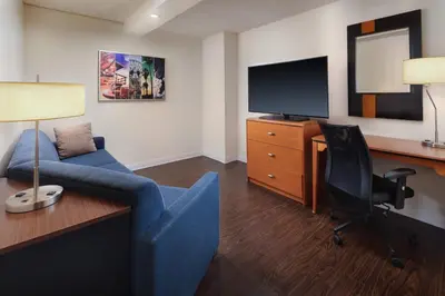 a living room with a blue couch and a desk with a television at Fairfield by Marriott Anaheim Resort in Anaheim