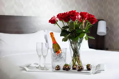 a table with a vase of roses and a bottle of champagne at Renaissance Los Angeles Airport Hotel in Los Angeles