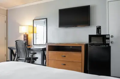 a hotel room with a bed and a desk with a television at The Buena Park Hotel & Suites in Buena Park
