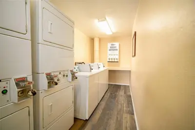 a small kitchen with white appliances and wooden floors at The Buena Park Hotel & Suites in Buena Park