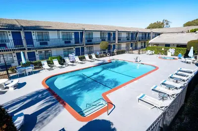 a large swimming pool with lounge chairs and a hotel at The Buena Park Hotel & Suites in Buena Park