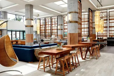 a restaurant with wooden tables and a blue couch at Westdrift Manhattan Beach, Autograph Collection in Manhattan Beach
