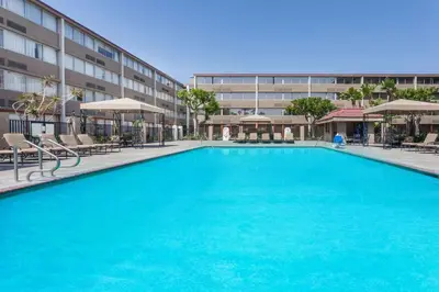 a large blue swimming pool in front of a building at Howard Johnson by Wyndham Fullerton/Anaheim Conference Cntr in Fullerton