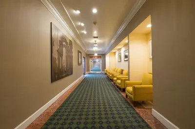 a corridor of a hospital with chairs and a carpet at Howard Johnson by Wyndham Fullerton/Anaheim Conference Cntr in Fullerton