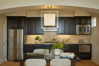 a kitchen with black cabinets and a table with chairs at Terranea Resort in Rancho Palos Verdes