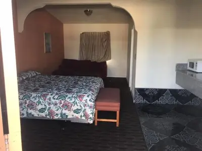 a bedroom with a bed and a chair in it at Galleria Inn Montclair/Ontario in Montclair