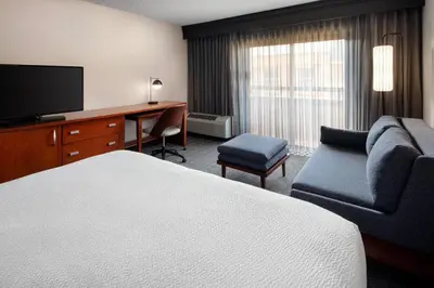 a hotel room with a bed and a desk and a television at Courtyard by Marriott Bakersfield in Bakersfield