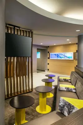 a lobby with two tables and a flat screen tv at SpringHill Suites Bakersfield in Bakersfield