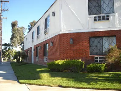 a red and white brick building with a grass yard at Palms Courtyard Inn in Westminster