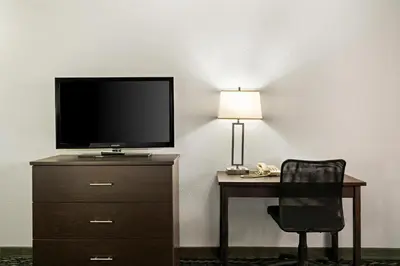 a desk with a tv and a chair and a lamp at Best Western Desert Villa Inn in Barstow