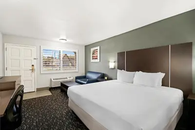 a hotel room with a large bed and a chair at Best Western Desert Villa Inn in Barstow