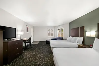 a hotel room with two beds and a flat screen tv at Best Western Desert Villa Inn in Barstow
