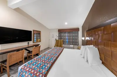 a hotel room with a large bed and a desk at Anaheim Discovery Inn and Suites in Anaheim