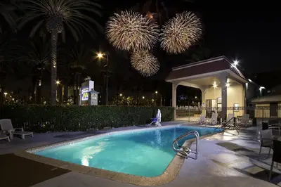 a swimming pool at night with fireworks in the background at Anaheim Discovery Inn and Suites in Anaheim