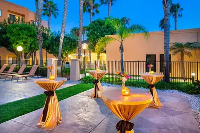 a patio with two tables with candles and palm trees at Sonesta Select Los Angeles Torrance South Bay in Torrance