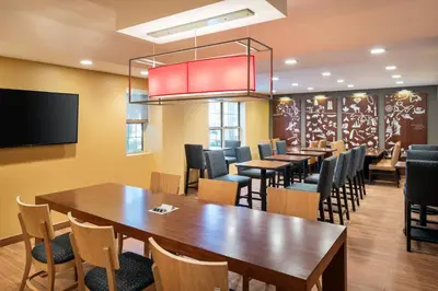 a dining room with tables and chairs and a flat screen tv at TownePlace Suites Los Angeles LAX Manhattan Beach in Hawthorne