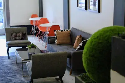 a living room with couches and tables and orange chairs at Libra Hotel in Los Angeles