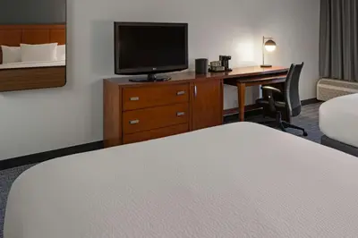 a hotel room with a bed and a desk with a television at Courtyard Anaheim Buena Park in Buena Park