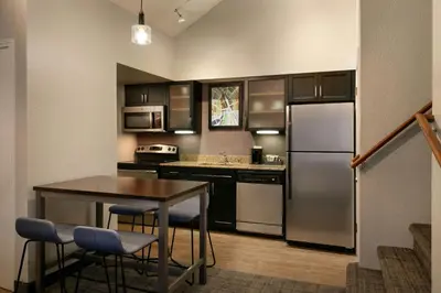 a kitchen with a table and a refrigerator at Residence Inn Pasadena Arcadia in Arcadia