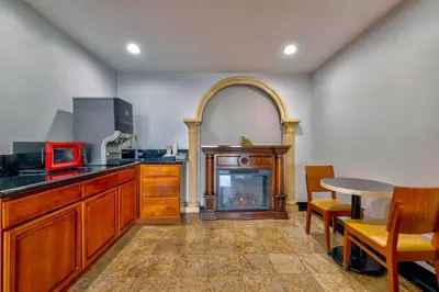 a kitchen with a fireplace and a table and chairs at Motel 6 South Gate CA in South Gate
