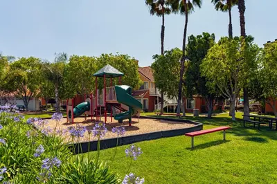 a park with a playground with slides and purple flowers at Clementine Hotel & Suites Anaheim in Anaheim